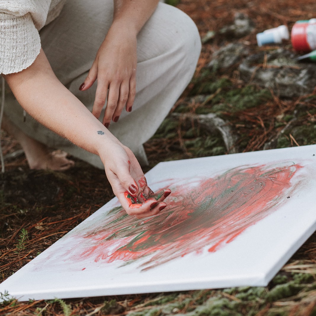 Alguien pintando en un lienzo con acuarela, con las manos.